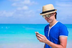 Young happy businessman with his phone on beach vacation photo