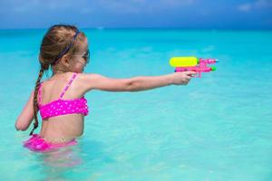 Happy little girl playing at beach during caribbean vacation photo