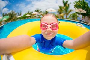 Little happy adorable girl in outdoor swimming pool photo