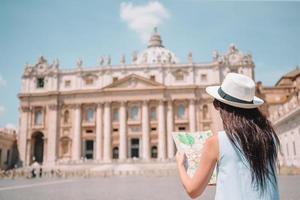 mujer joven feliz con mapa de la ciudad en ciudad del vaticano y st. basílica de san pedro, roma, italia. foto