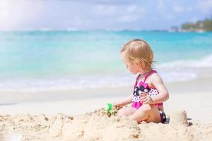 Adorable little girl have fun at tropical beach during vacation photo