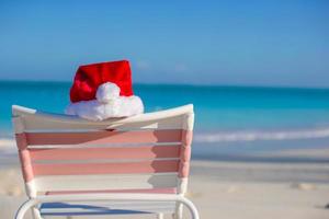 cerrar gorro de Papá Noel en silla longue en playa tropical foto