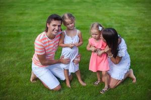 Portrait young family of four sit on the grass and have fun photo