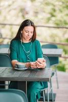 Young woman with smart phone while sitting alone in coffee shop during free time photo