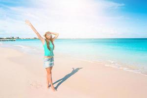 Young beautiful woman having fun on tropical seashore. Happy girl background the blue sky and turquoise water in the sea on caribbean island photo