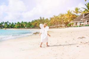 Beautiful young girl wearing angel wings on the beach photo