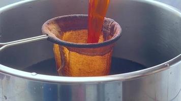 närbild filtrera svart te med te filtrera väska efter kokande. efter kokande. filtrera en te in i de rostfri stål pott förbi en brun trasa te sil. video