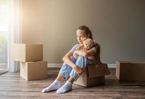 Beautiful young girl moving in new house with cardboard boxes photo