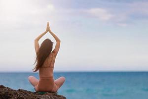 Young woman with long hair practicing yoga on the beach photo