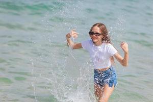 Happy cute girl splashing and having fun in shallow water photo