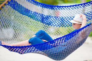 Beautiful woman relaxing at hammock on tropical beach photo