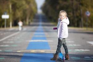 Adorable little girl have fun on the scooter outdoors photo