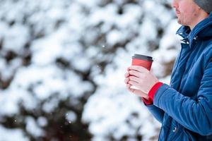 Happy man drinking coffee outdoors in winter time photo