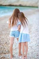 Two little happy girls have a lot of fun at tropical beach playing together photo