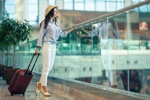 mujer joven con sombrero con equipaje en el aeropuerto internacional. foto