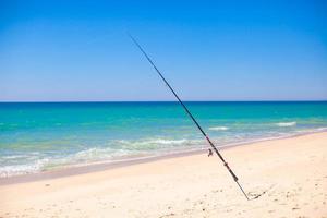 Fishing rod in white sand on tropical beach, Portugal photo