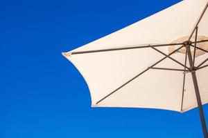 Part of white umbrella on background blue sky at the beach photo