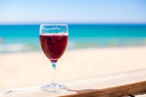 Glass of red wine against the turquoise sea photo