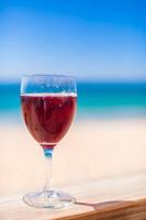 Glass of red wine against the turquoise sea photo
