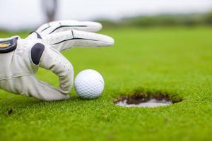 Golf player man pushing golfball into the hole photo