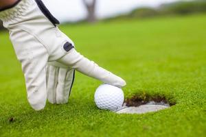 Golf player man pushing golfball into the hole photo