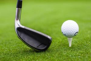 Golf tee ball club driver in green grass course closeup photo