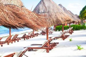 Paradise view of nice tropical empty sandy plage with umbrella and beach chair photo