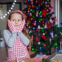 Charming little girl in gloves baking Christmas cakes photo