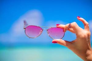 Close up of colorful pink sunglasses on tropical beach photo