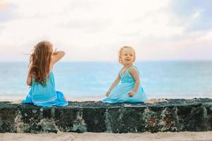 Little happy funny girls have a lot of fun at tropical beach playing together. photo