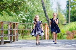 Adorable little school girls outdoors in warm september day. Back to school. photo