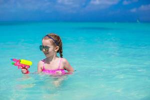 Happy little girl playing with toys during caribbean vacation photo