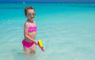 Happy little girl playing at beach during caribbean vacation photo