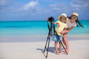 Little girl with camera and young mother on beach photo