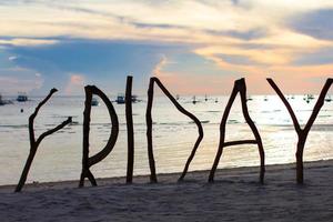 Perfect white sandy beach on tropical island with wooden letters silhouette made Friday word photo