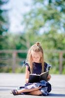 Adorable little school girl with notes and pencils outdoor. Back to school. photo