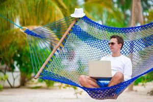 Man with laptop at hammock on tropical vacation photo