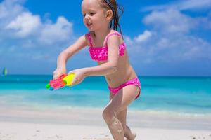 Happy little girl playing with toys at beach during vacation photo