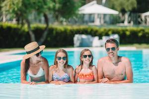 familia feliz de cuatro en la piscina al aire libre foto