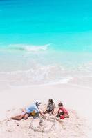 Family making sand castle at tropical white beach. photo