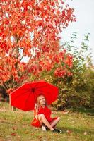 Happy child girl laughs under red umbrella photo