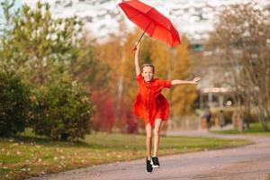 niña feliz ríe bajo el paraguas rojo foto