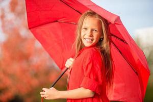 Happy child girl laughs under red umbrella photo