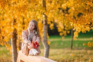 retrato de niña adorable con ramo de hojas amarillas en otoño foto