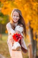 retrato de niña adorable con ramo de hojas amarillas en otoño foto