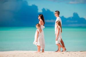 Happy beautiful family of four on white beach photo