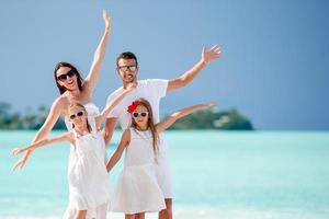 feliz hermosa familia de cuatro en la playa foto