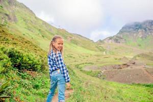Beautiful happy little girl in mountains in the background of fog photo