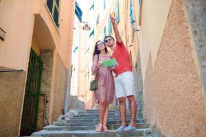 pareja de jóvenes turistas que viajan de vacaciones al aire libre en vacaciones italianas. familia caucásica con mapa de la ciudad en busca de atracciones foto