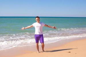 Young man spread his hands on tropical beach photo